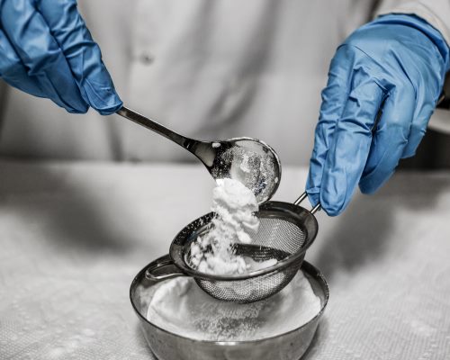 Un formulateur crée en laboratoire un prototype de produit cosmétique avec des ingrédients en poudre.